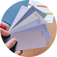 Hand holding a fan on color swatches in soft lavenders, blues and neutrals.